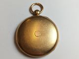 a close up of a gold pocket watch on a white surface