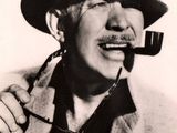 black and white photo of a man in a hat with a pipe in his mouth