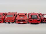 five red cars lined up in a row on a white surface