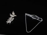 two pieces of jewelry on a black surface with a black background