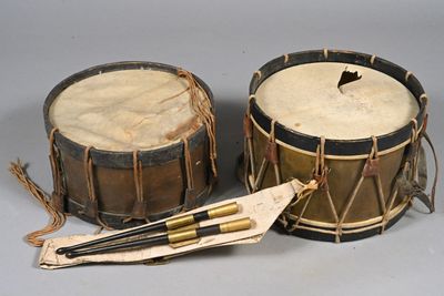 deux tambours avec des baguettes et une feuille de papier posée sur une table