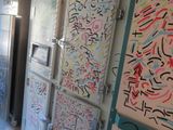 des réfrigérateurs et des congélateurs couverts de graffitis dans une cuisine au sol carrelé de blanc