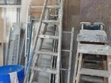 a pile of old ladders and other items in a warehouse