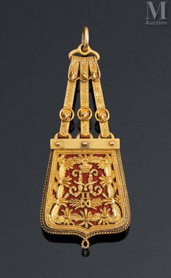a close up of a gold and red pendant on a black background