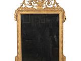un miroir avec un cadre doré et un homme debout devant