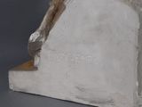 statue of a man sitting on top of a book on a gray surface