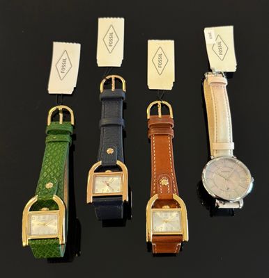 quatre montres de couleurs différentes sont alignées sur une surface noire