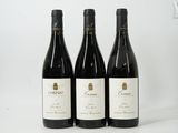 trois bouteilles de vin rouge sont alignées sur une surface blanche