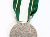 a silver medal with a green and white ribbon
