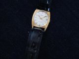a gold and black watch sitting on top of a black cloth