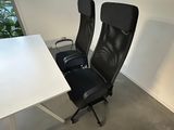 a white table with two black chairs and a white table
