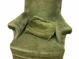 une chaise verte aux accoudoirs frangés, sur laquelle est posé un coussin