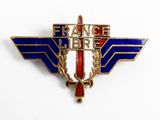 un gros plan d'un insigne posé sur une surface blanche, orné d'un motif rouge, blanc et bleu