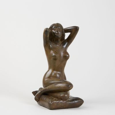 a bronze statue of a woman sitting on a pillow