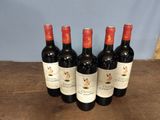 six bottles of red wine are lined up on a wooden table