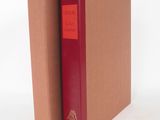 un livre marron à la couverture rouge posé sur une surface blanche