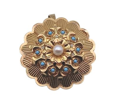 une photo en gros plan d'une broche ornée d'une perle