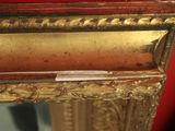 a mirror with a gold frame and a red wall in the background