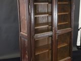 an old wooden cabinet with glass doors on a black surface