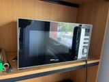 a microwave sitting on a shelf in the corner of a room
