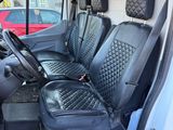 the interior of a white van with black seats and a red car in the background