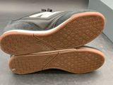 pair of grey and white sneakers with brown soles on a gray surface