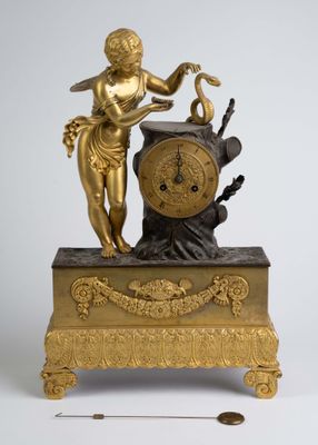 une statue en or représentant une femme tenant un oiseau et une horloge