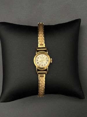 un gros plan d'une montre en or posée sur un coussin noir