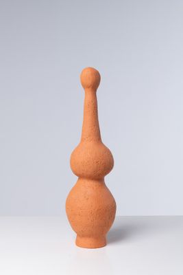 un petit vase orange posé sur une table blanche