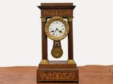 une petite horloge en bois posée sur une table, sur fond blanc