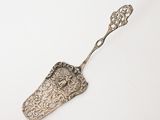 an old silver spoon with a handle on a white surface