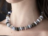 woman wearing a black top and a necklace with white and blue beads