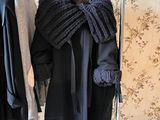 a rack with coats and scarves on it in front of a wallpapered wall