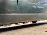 a cat that is sitting on the ground next to a car