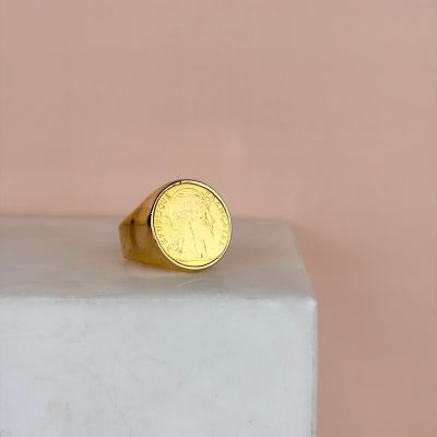 une bague en forme de pièce d'or posée sur un bloc de marbre