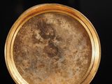 a close up of a gold plate with a black background