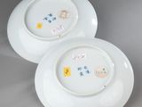 pair of white plates with designs on them sitting on a gray surface