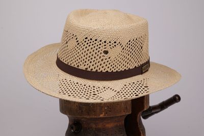 un chapeau de paille posé sur un support en bois, sur lequel se trouve un chapeau