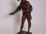 une statue représentant un homme coiffé d'un chapeau, posée sur un socle