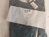 deux paires de pantalons verts pour homme, dans des sacs en plastique, posées sur une table