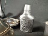 a silver vase sitting on a table next to other silver objects