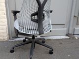 a black and white office chair sitting on the pavement