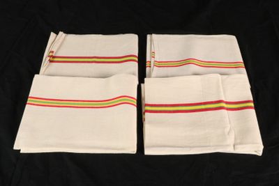 four white napkins with multi colored stripes on them on a black background