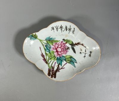 une petite assiette sur laquelle sont peints un oiseau et des fleurs