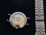 a silver watch with a yellow face on a black surface