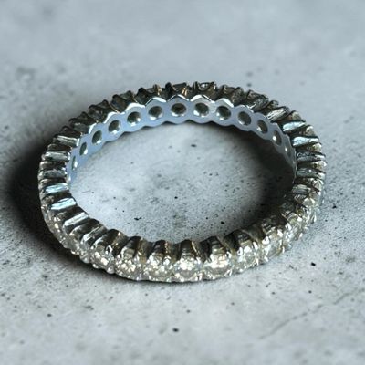 un gros plan d'une bague en diamant posée sur une surface en béton