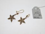 une paire de boucles d'oreilles ornées d'un papillon, posée à côté d'une étiquette de prix