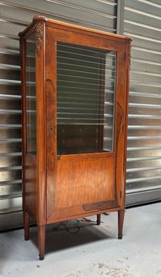 an old wooden cabinet with a glass door on it
