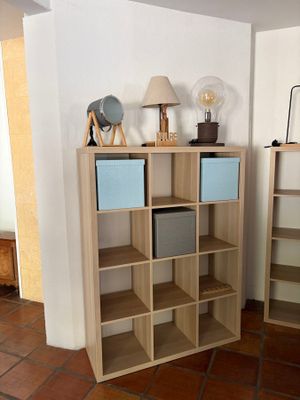 two bookshelves in the corner of a room with a lamp on top of them