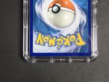 a pokemon card in a plastic case on a table